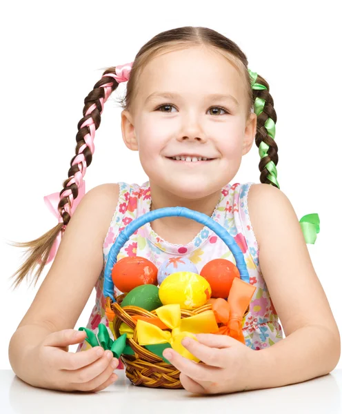 Kleines Mädchen mit Korb voller bunter Eier — Stockfoto