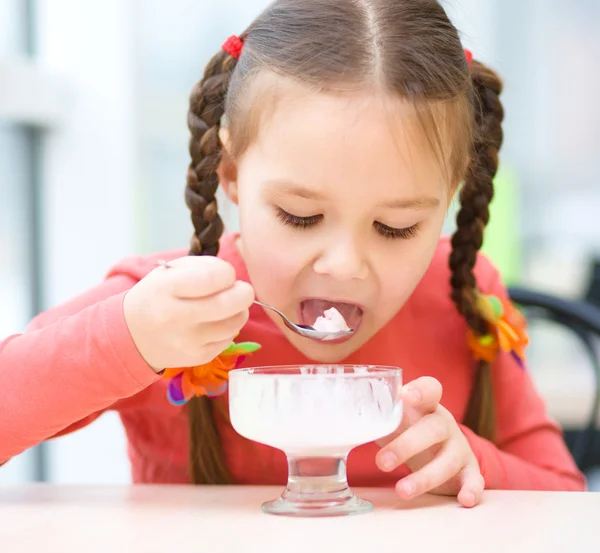 Pikkutyttö syö jäätelöä salongissa. — kuvapankkivalokuva