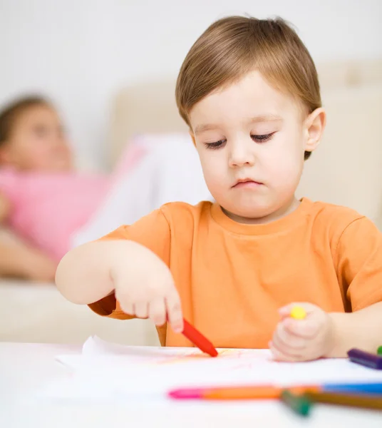 Маленький хлопчик малює на білому папері — стокове фото