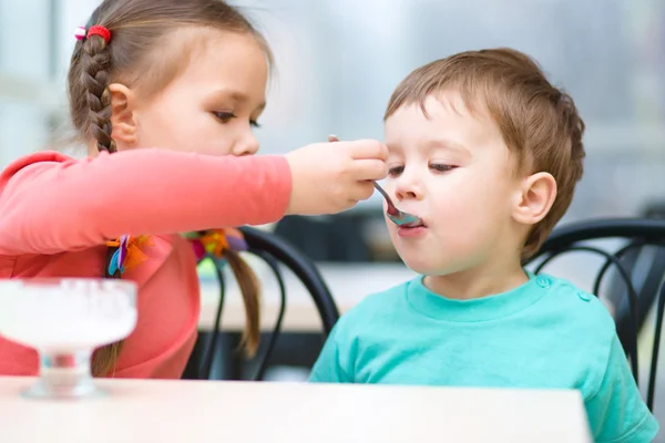 Chica está alimentando a su hermano pequeño con helado —  Fotos de Stock