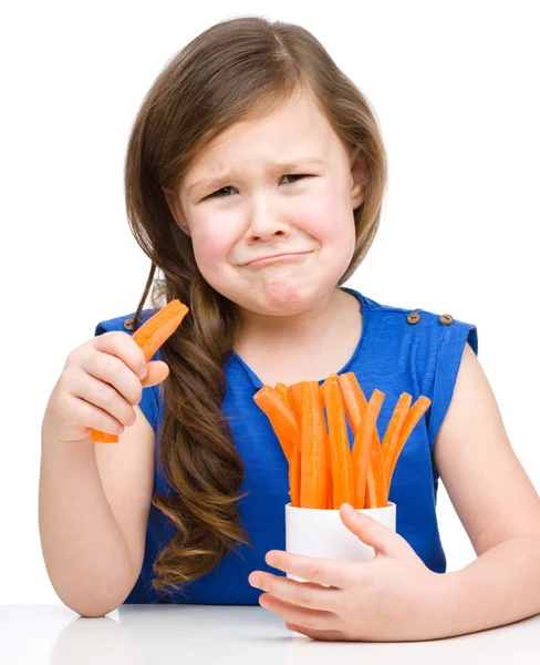 Cute little girl is eating carrot — Stock Photo, Image