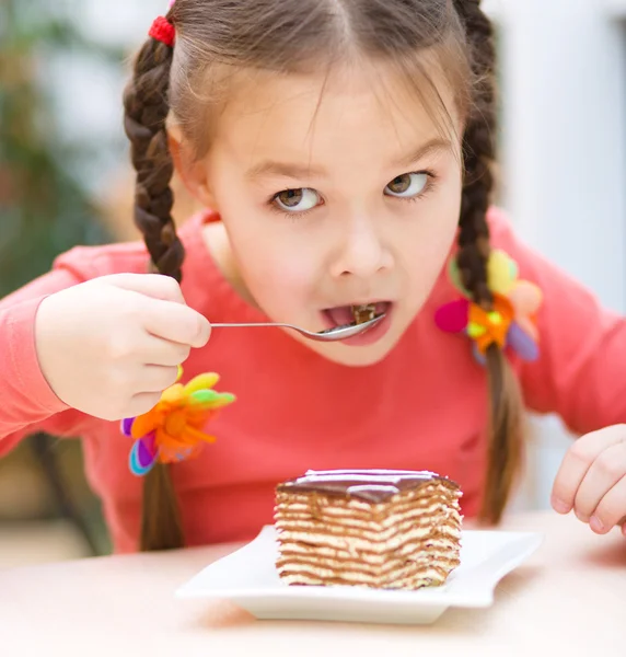 Pikkutyttö syö kakkua salongissa. — kuvapankkivalokuva