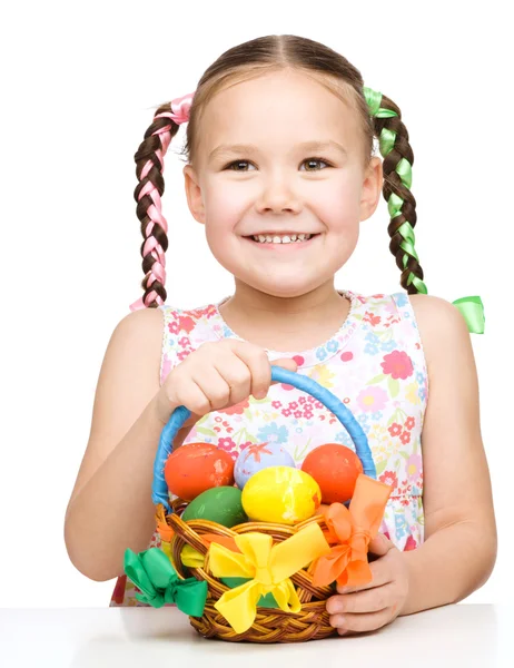 Kleines Mädchen mit Korb voller bunter Eier — Stockfoto