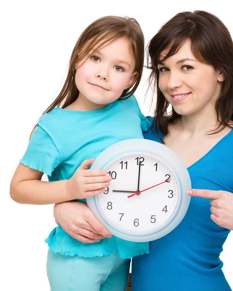 Kleines Mädchen und ihre Mutter halten eine große Uhr in der Hand — Stockfoto