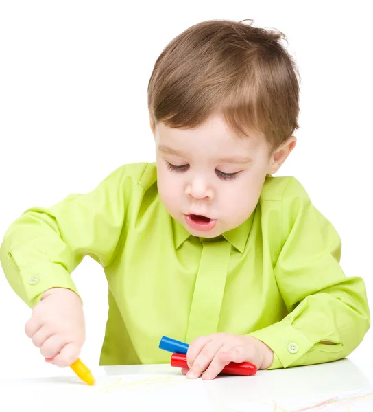 Little boy is drawing on white paper using crayon — Stock Photo, Image