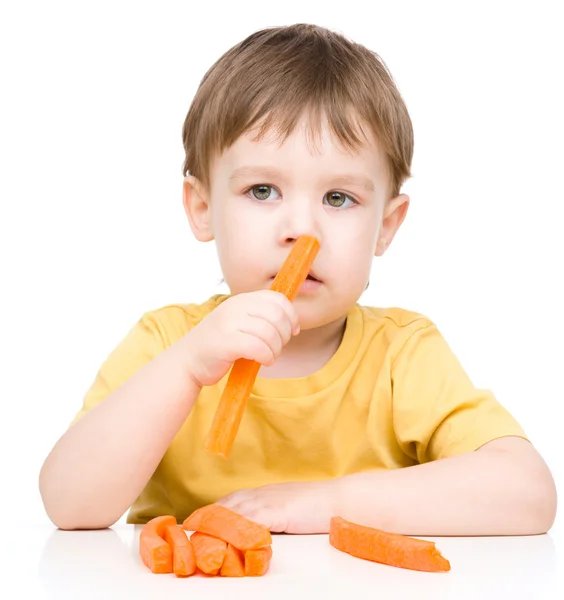 Menino está comendo cenoura — Fotografia de Stock