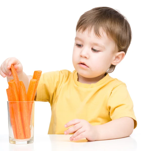 Little boy is eating carrot — Stock Photo, Image