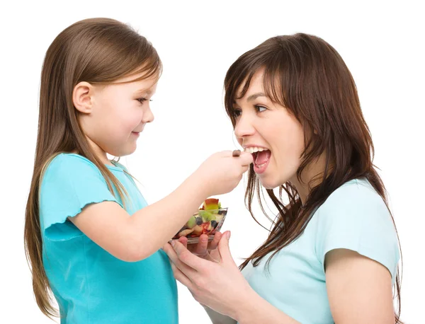 Daughter is feeding her mother with fruit salad — Stock Photo, Image