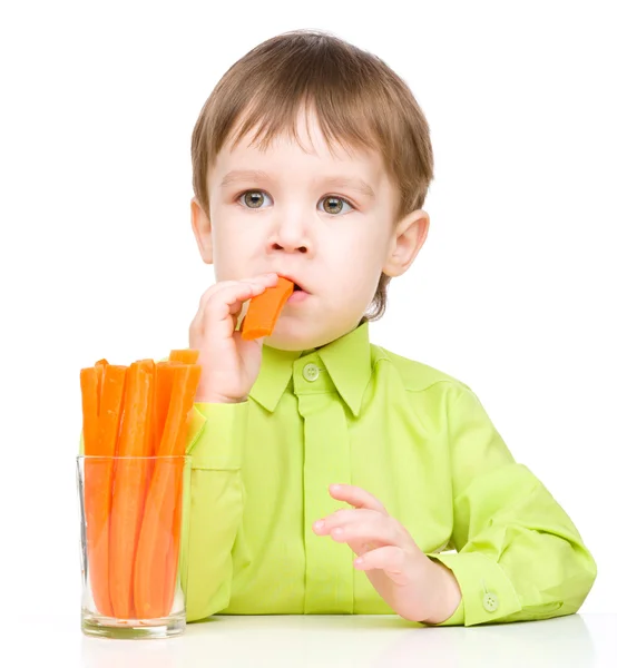 Menino está comendo cenoura — Fotografia de Stock