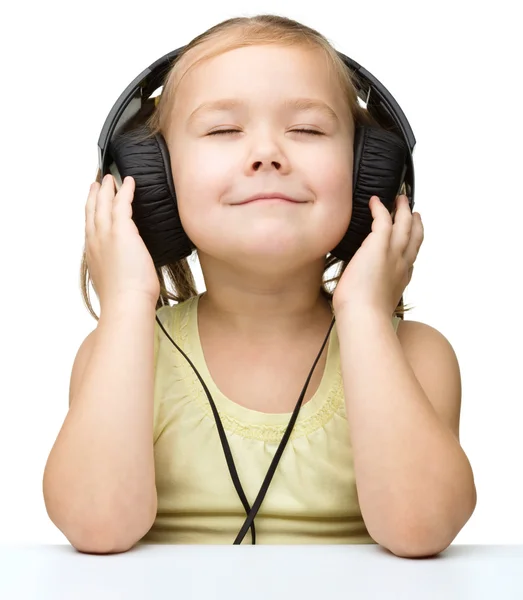 Klein meisje is genieten van muziek met behulp van de hoofdtelefoon — Stockfoto