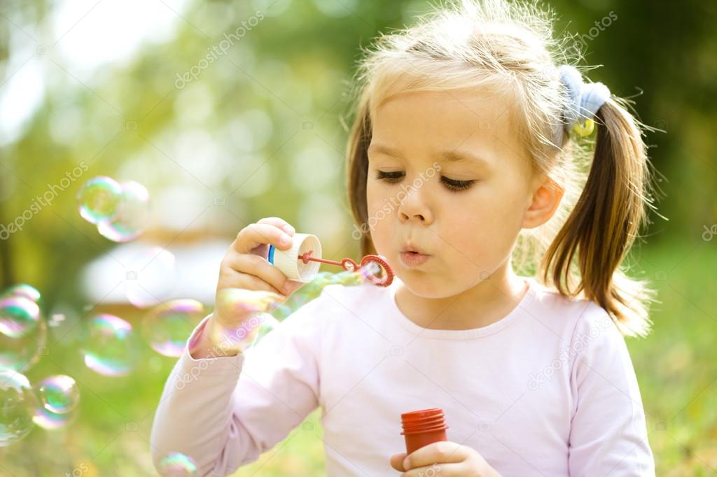 Little girl is blowing a soap bubbles
