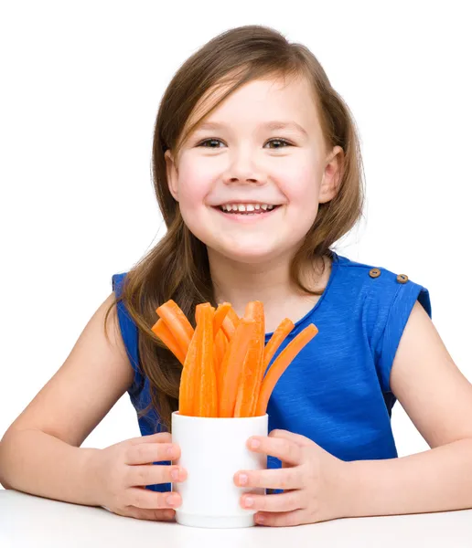 Cute little girl is eating carrot — Stock Photo, Image