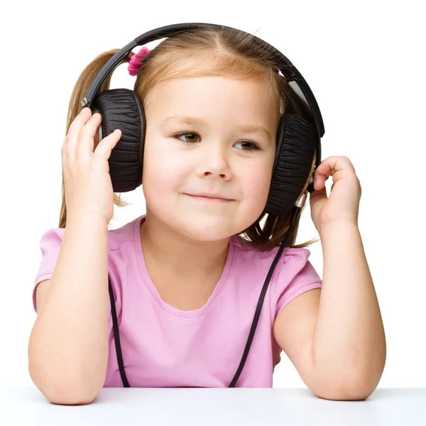 Little girl is enjoying music using headphones Stock Picture