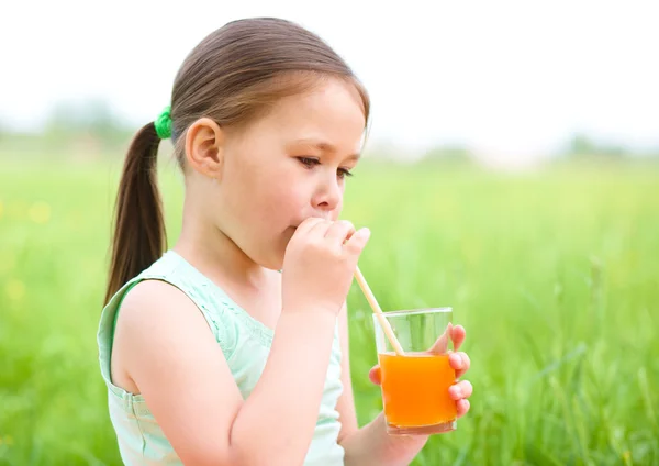 Little girl is drinking orange juice — Stock Photo, Image