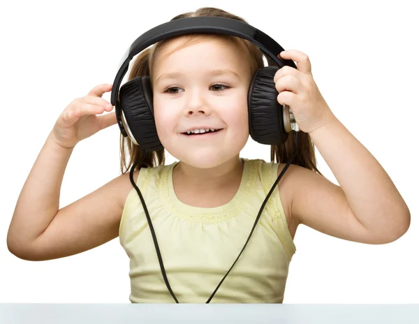 Little girl is enjoying music using headphones — Stock Photo, Image