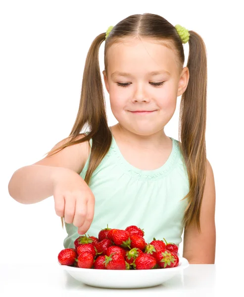 Happy little girl is eating strawberries — Stock Photo, Image