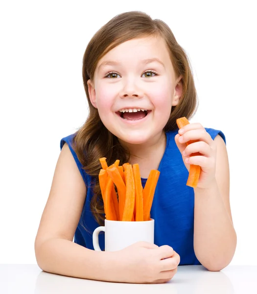 Cute little girl is eating carrot — Stock Photo, Image