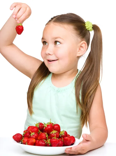 Cheerful little girl is eating strawberries — Stock Photo, Image