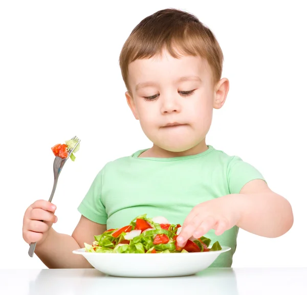 Menino bonito está comendo salada de legumes — Fotografia de Stock