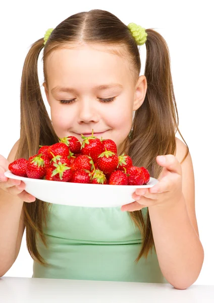 Cheerful little girl is smelling strawberries — Stock Photo, Image