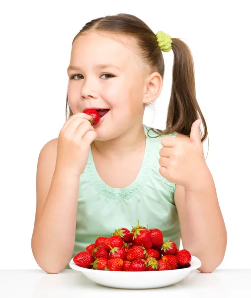 Happy little girl is eating strawberries — Stock Photo, Image