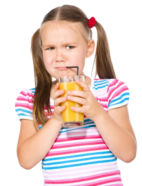 Маленькая девочка неохотно пьет апельсиновый сок — стоковое фото