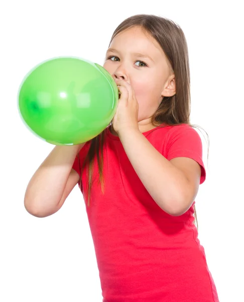 Маленькая девочка надувает зелёный шарик — стоковое фото