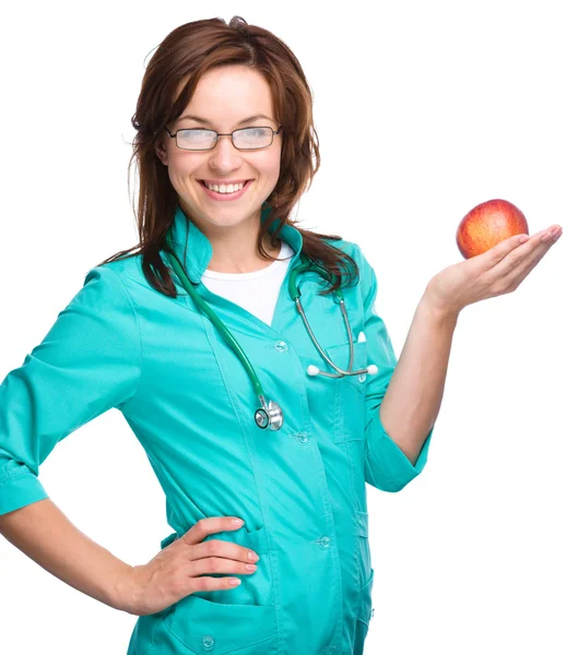 Young lady doctor is holding a red apple — Stock Photo, Image