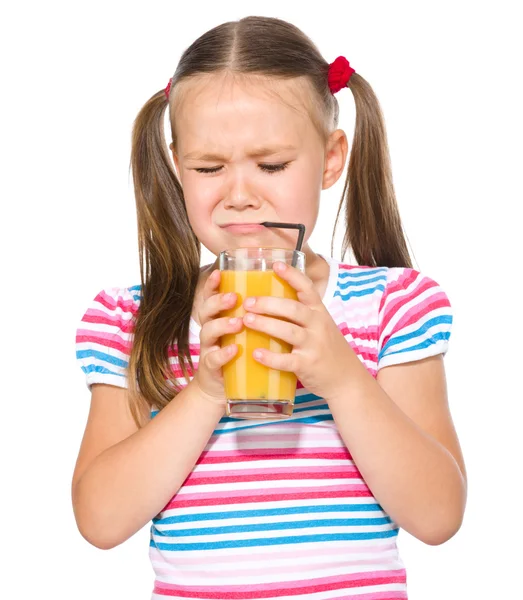 Маленькая девочка неохотно пьет апельсиновый сок — стоковое фото