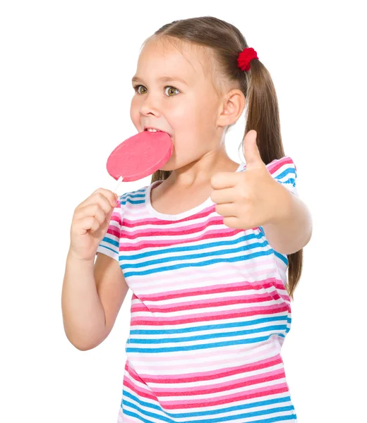 Bambina con lecca-lecca mostrando pollice in su gesto — Foto Stock