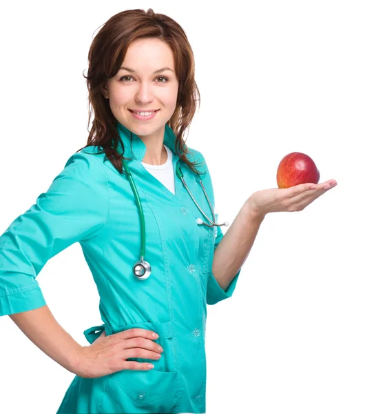 Junge Ärztin hält einen roten Apfel — Stockfoto