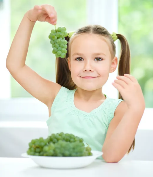 Sevimli küçük kız yeşil üzümleri yiyor — Stok fotoğraf