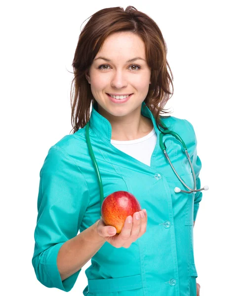 Jovem médica está segurando uma maçã vermelha — Fotografia de Stock