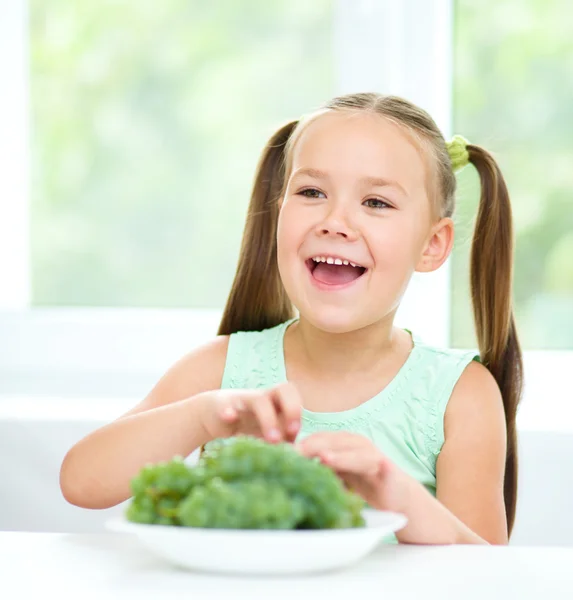 Cute little girl is eating green grapes — Stock Photo, Image