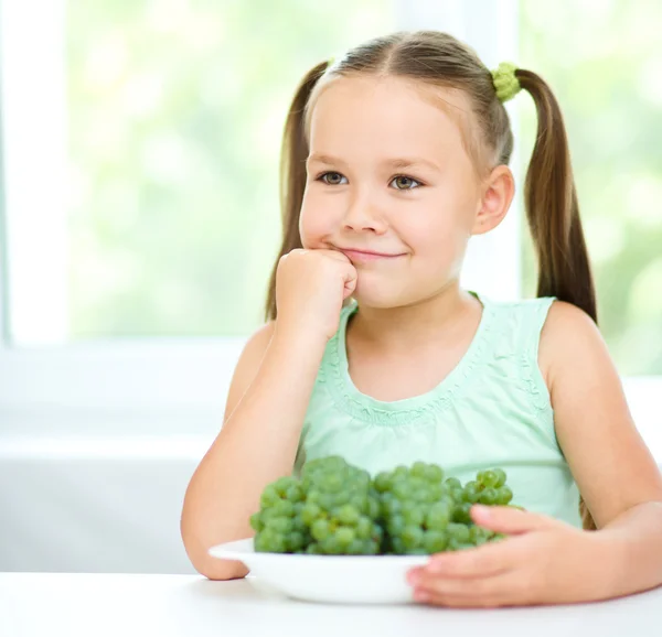 Söt liten flicka äter gröna druvor — Stockfoto