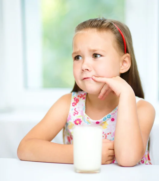 Sad little girl with a glass of milk — Stock Photo, Image