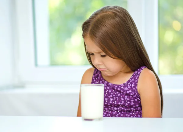 Sad little girl with a glass of milk — Stock Photo, Image
