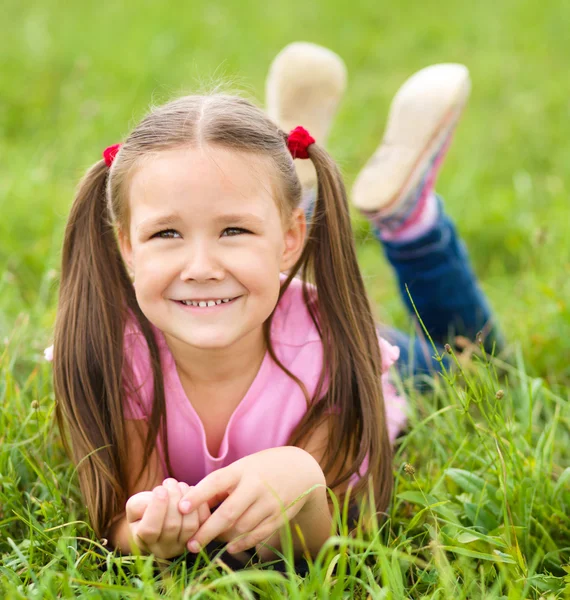 Porträt eines kleinen Mädchens auf grünem Gras liegend — Stockfoto