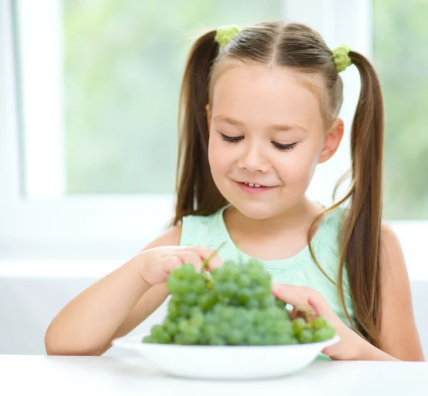Cute little girl is eating green grapes — Stock Photo, Image