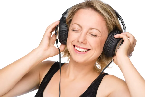 Jonge vrouw genieten van muziek met behulp van de hoofdtelefoon — Stockfoto