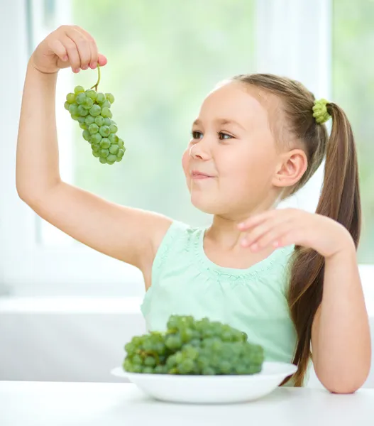 Sevimli küçük kız yeşil üzümleri yiyor — Stok fotoğraf