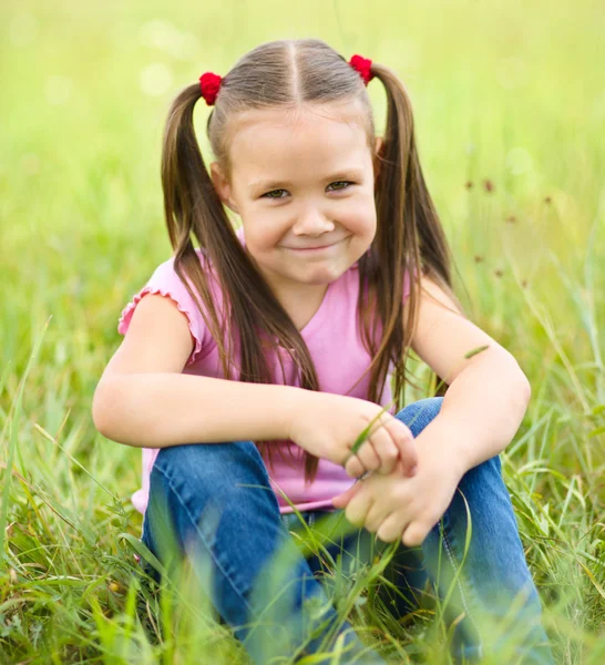 Ritratto di una bambina seduta sull'erba verde — Foto Stock