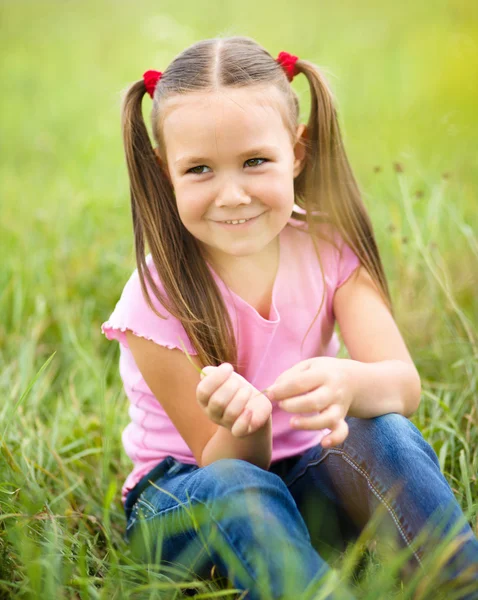 Porträtt av en liten flicka sitter på grönt gräs — Stockfoto