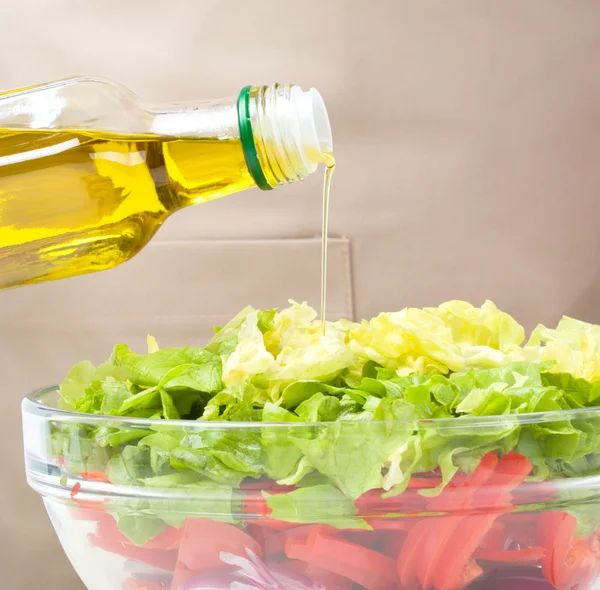 Cozinheiro está derramando azeite em salada — Fotografia de Stock
