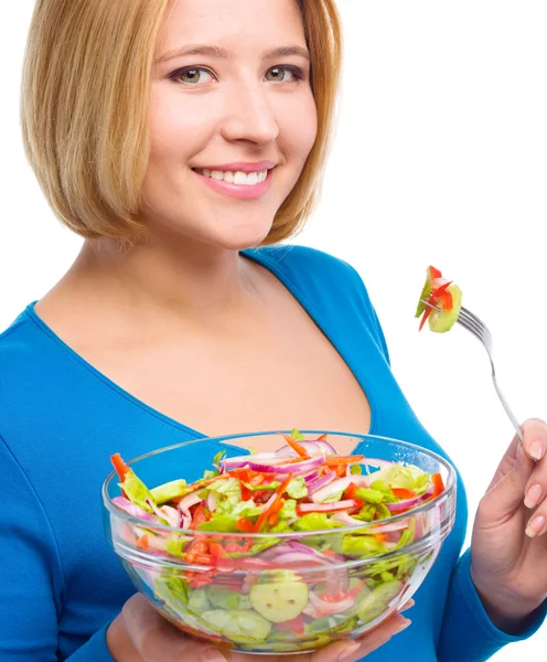 Jovem mulher atraente está comendo salada usando garfo — Fotografia de Stock