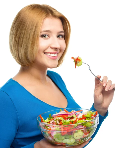 Jovem mulher atraente está comendo salada usando garfo — Fotografia de Stock