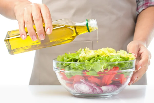 Cozinheiro está derramando azeite em salada — Fotografia de Stock