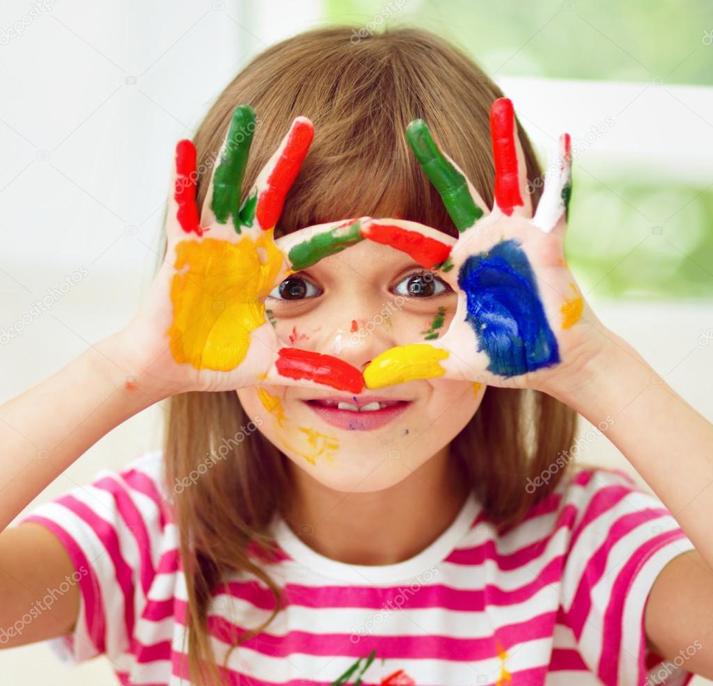 Portrait of a cute girl playing with paints