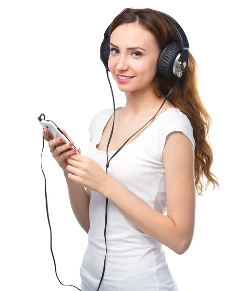 Jonge vrouw genieten van muziek met behulp van de hoofdtelefoon — Stockfoto