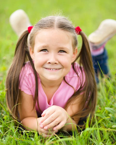 Portrait of a little girl laying on green grass — Stock Photo, Image